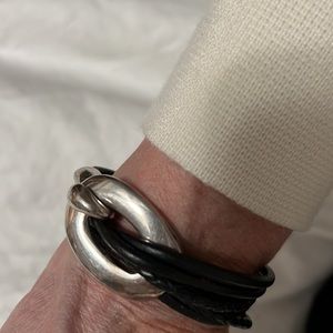 Black leather bracelet with silver tone metal closure.